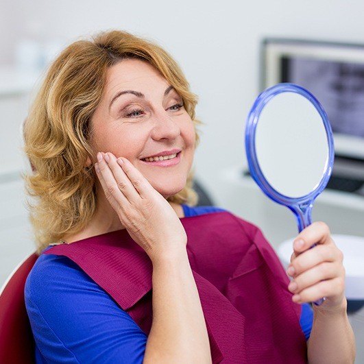 Woman looking at her smile after mini dental implant tooth  replacement