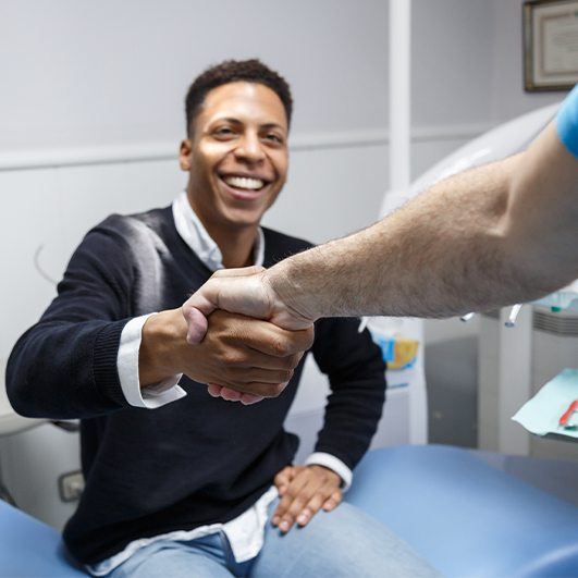 Man shaking hands with dentist after all on four tooth replacement