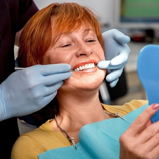 Woman receiving dental exam after dental implant tooth replacement