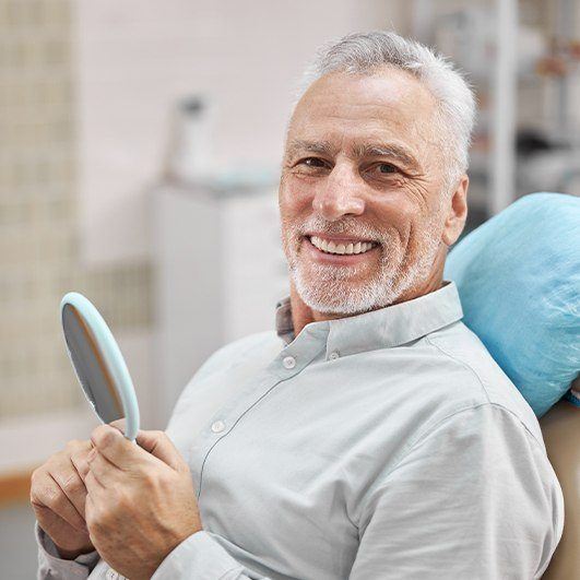 Man in dentist's office smiling after dental implant tooth replacement