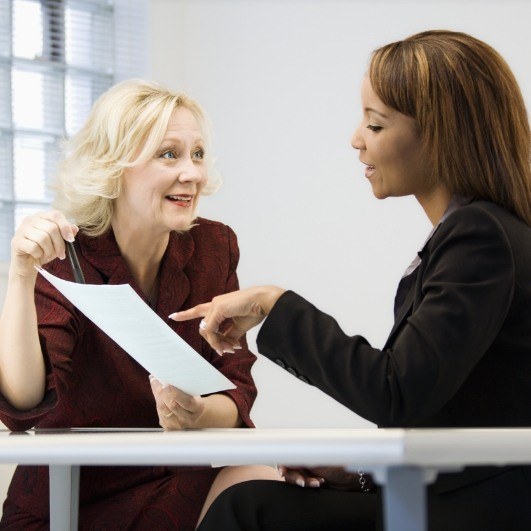 two ladies at a desk comparing dental implant costs