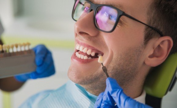 Man with missing tooth looking at dental implant replacement tooth shades