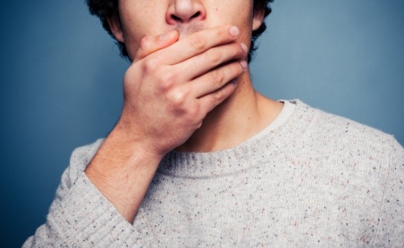 Man in need of dental implant salvage covering his mouth