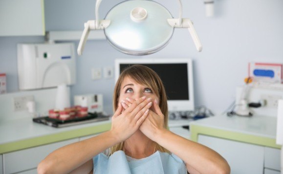 Woman in need of dental implant tooth replacement covering her mouth