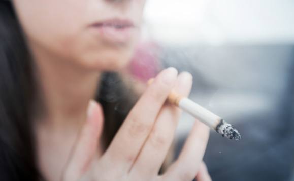 Person smoking a cigarette after dental implant tooth replacement