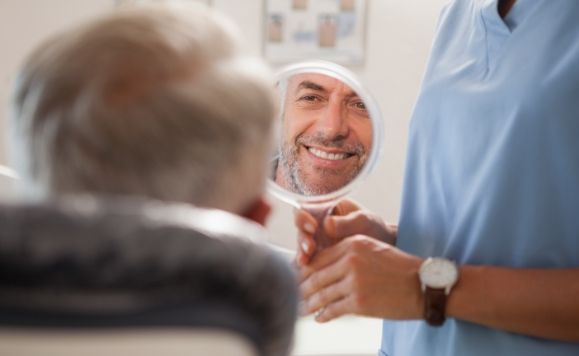 Man looking at his smile after dental implant denture placement