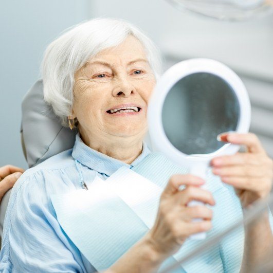 Woman looking at her smile  after denture stabilization treatment