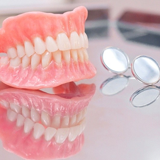 Full upper and lower dentures resting on tabletop