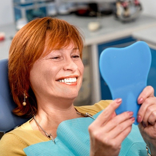 Woman using mirror to admire her new denture