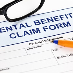 Dental benefits claim form with glasses and pen