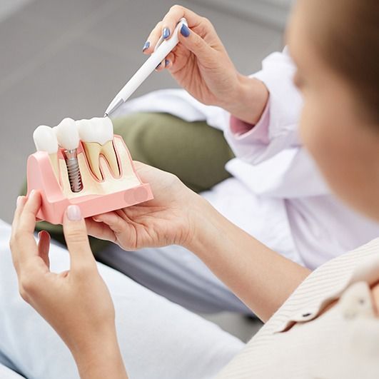 Dentist and patient looking at dental implant model during initial consultation