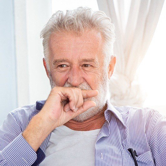 Man in need of dental implant tooth replacement hiding his smile