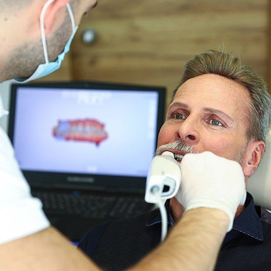 Oral surgeon capturing images of a patient's smile during dental implant tooth replacement