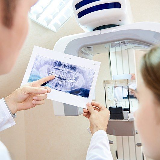 Dentist explaining how dental implant salvage in Houston works with X-ray