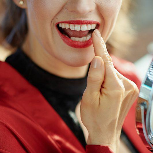 Woman pointing to her new dental implant in Houston