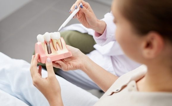 Dentist showing patient a dental implant model