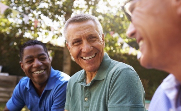 Man with dental implant supported replacement tooth smiling with friends