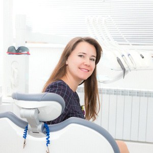 Happy female patient sitting up in dental chair