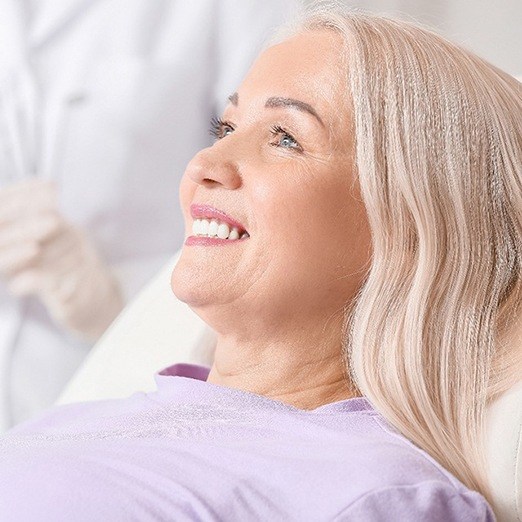 Middle-aged woman in dental chair, smiling during appointment