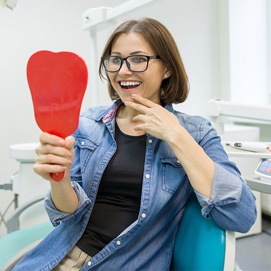 Woman looking at her smile in the mirror