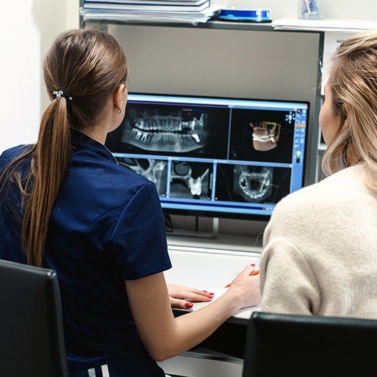 Dental team member and patient reviewing C T scan surgical guide