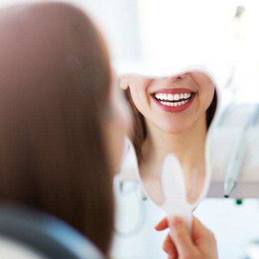 Woman looking at smile after C T scan guided dental implant tooth replacement surgery