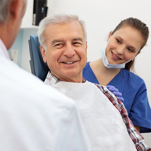 Man in dental chair smiling at dentist during dental implant preparation