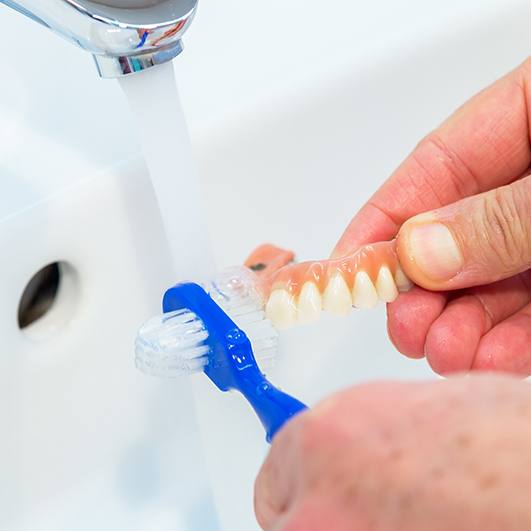 Patient brushing removable dental implant denture