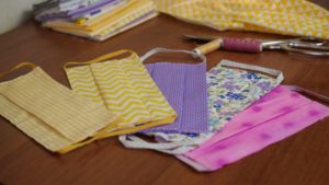 five homemade cloth face masks laid out on table