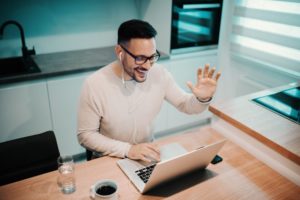 man waving to oral surgeon’s team during video call