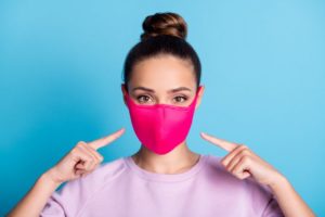 woman wearing pink face mask to visit oral surgeon