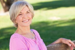 Mature woman smiling with dental implants after menopause