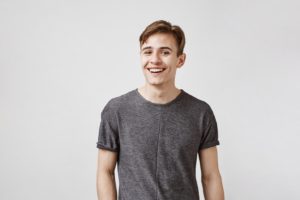 Smiling adolescent boy, wondering, “Can teenagers get dental implants?”