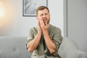 Man on sofa, experiencing sensitivity in a dental implant