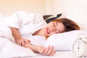 Woman sleeping in bed, grinding her teeth