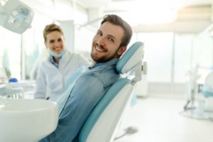 Happy male dental patient sitting in treatment chair