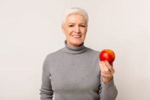 Smiling senior woman holding an apple