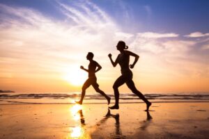 Couple jogging on the beach at sunset