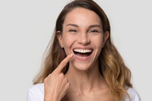 Happy young woman pointing at her teeth