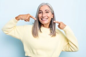 Smiling senior woman pointing at her teeth