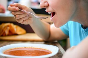 Person enjoying a bowl of tomato soup